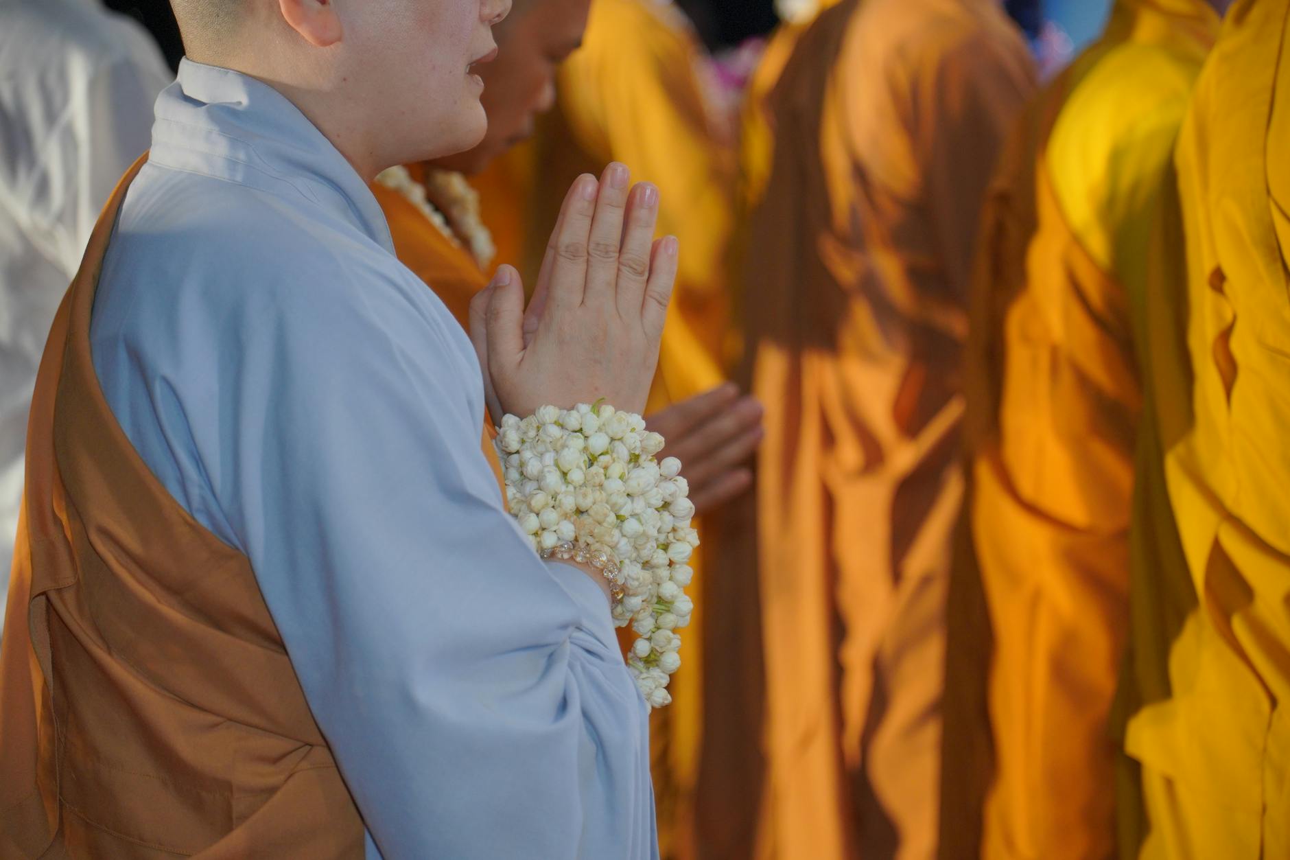 A Thai devotee dressed in white offering a candle to monks at a temple ceremony during Khao Phansa