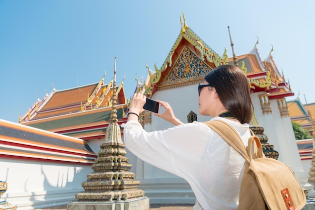 Tourist using her smartphone at Wat Pho temple in Bangkok