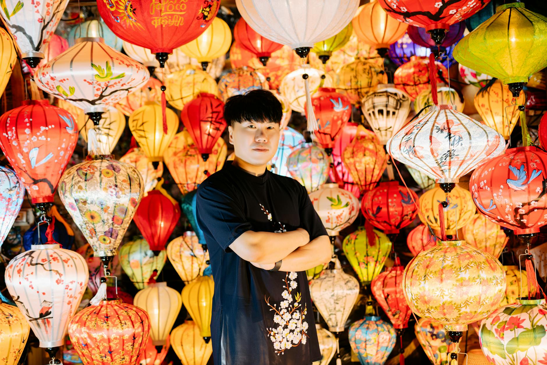 The festival street at night with illuminated hand-painted umbrellas glowing above food stalls and visitors