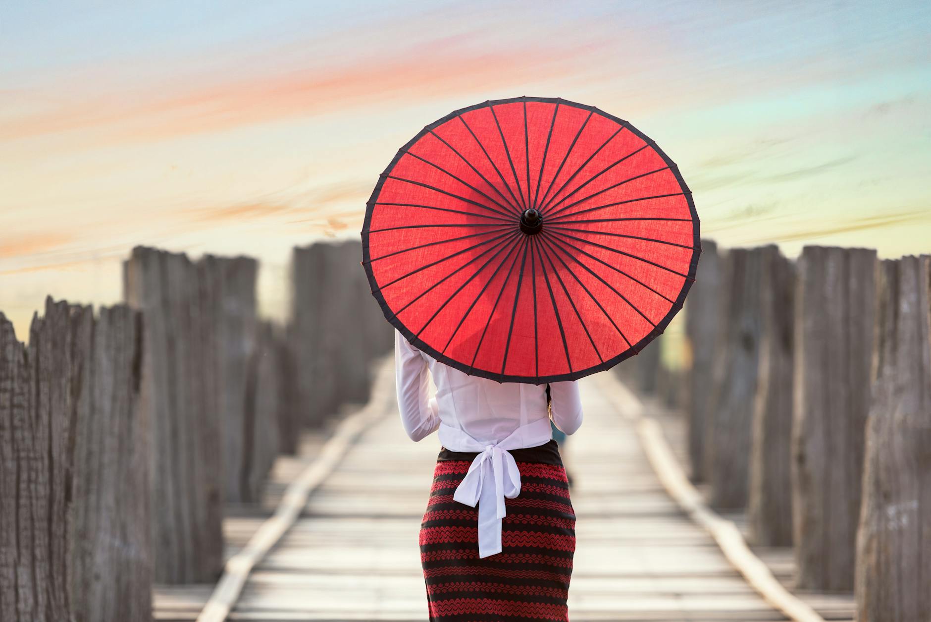 A contestant in the Miss Bo Sang pageant holding an elaborate hand-painted umbrella while wearing traditional Lanna silk