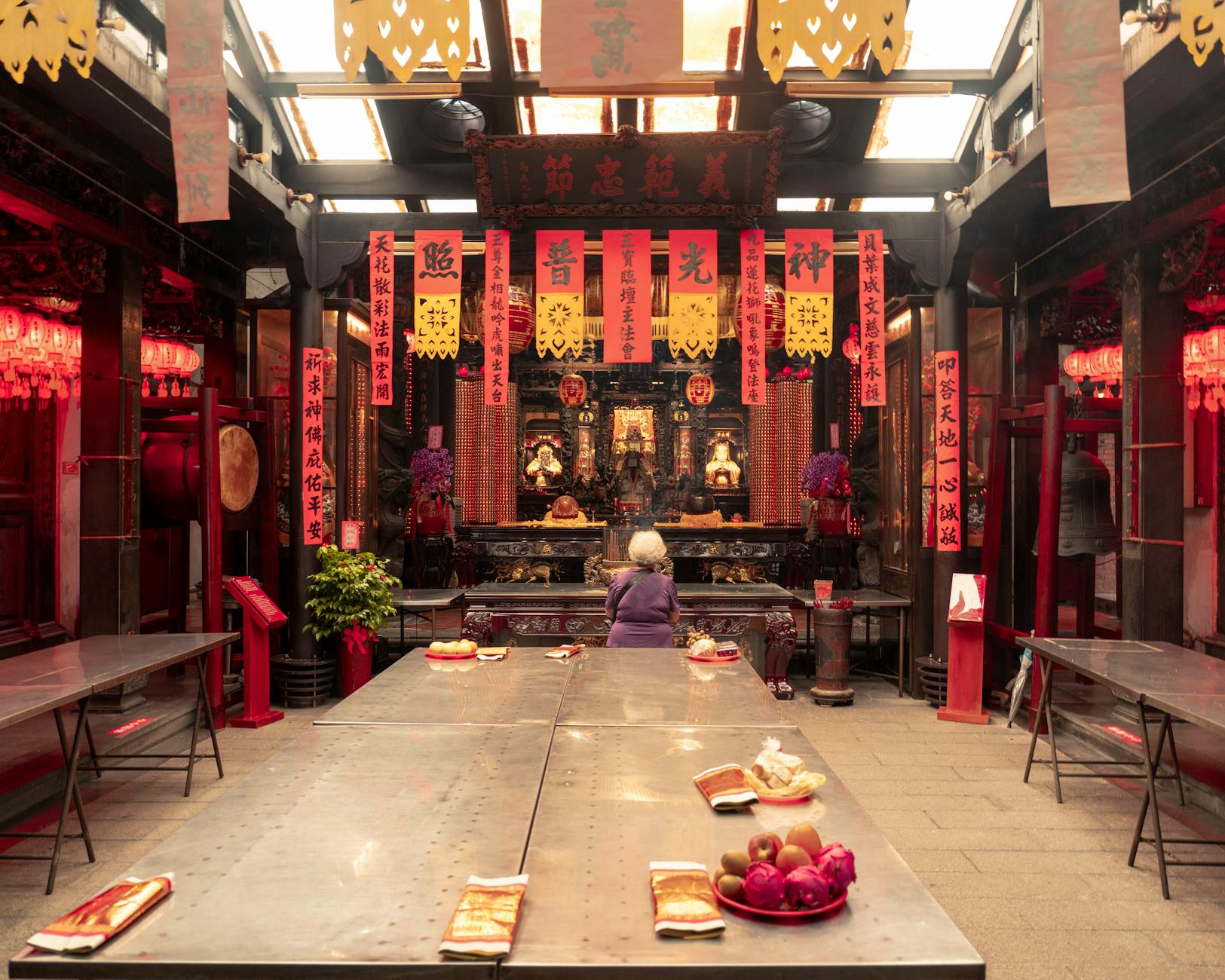 Devotees lighting incense and making offerings at an altar inside a Chinese temple in Thailand