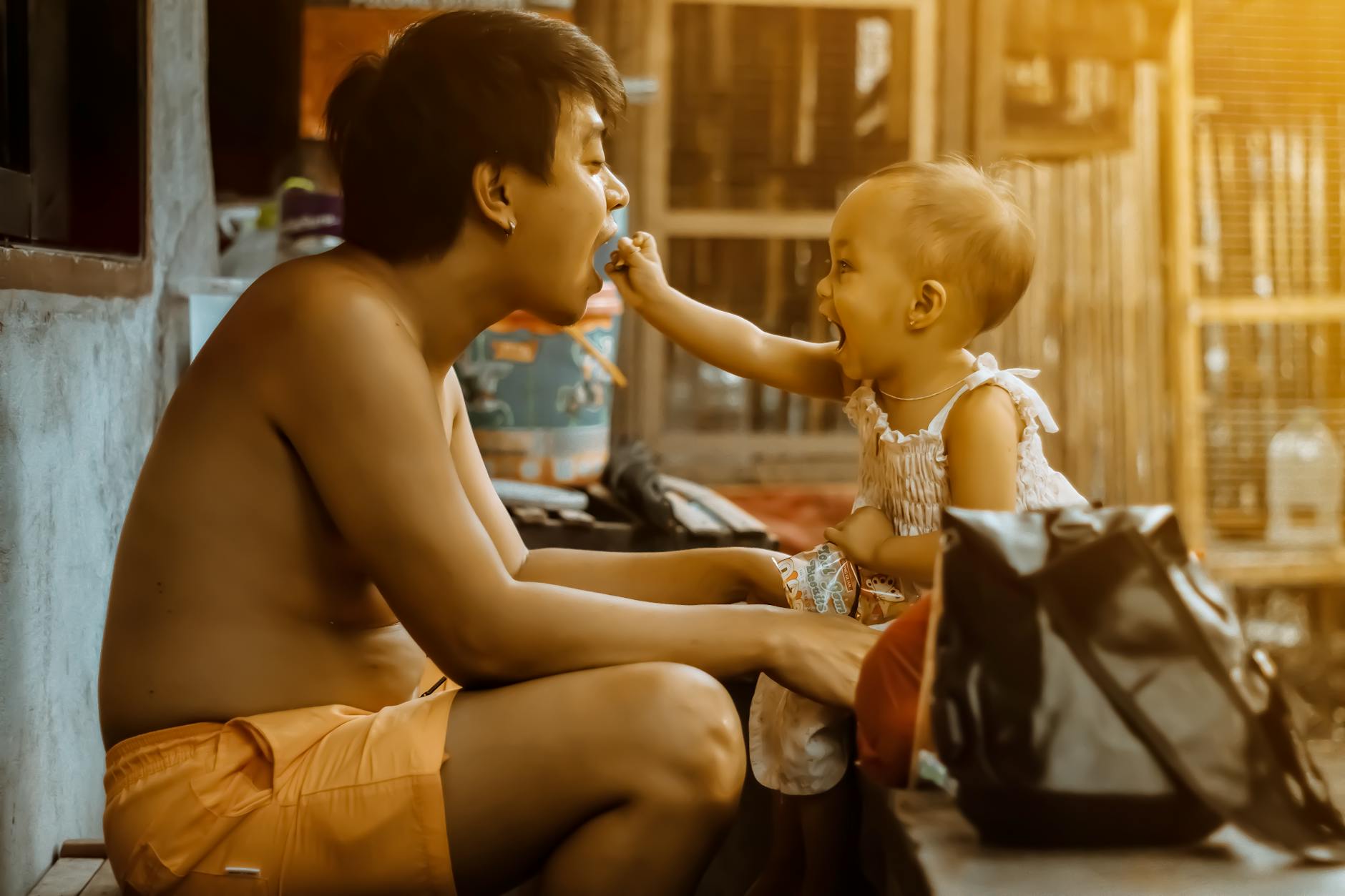 A father kneeling before his young child who is presenting him with a flower garland on Father's Day in Thailand