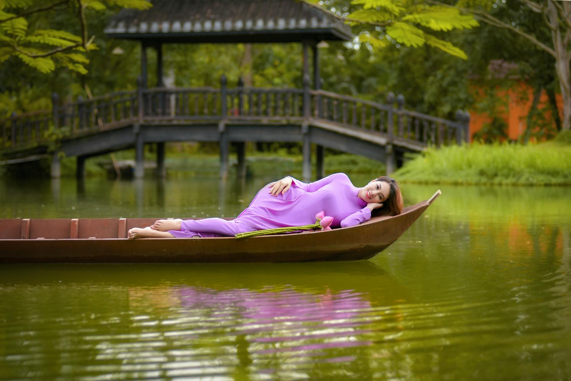 A woman gently placing a krathong into the river during Loy Krathong as candlelight reflects on the water
