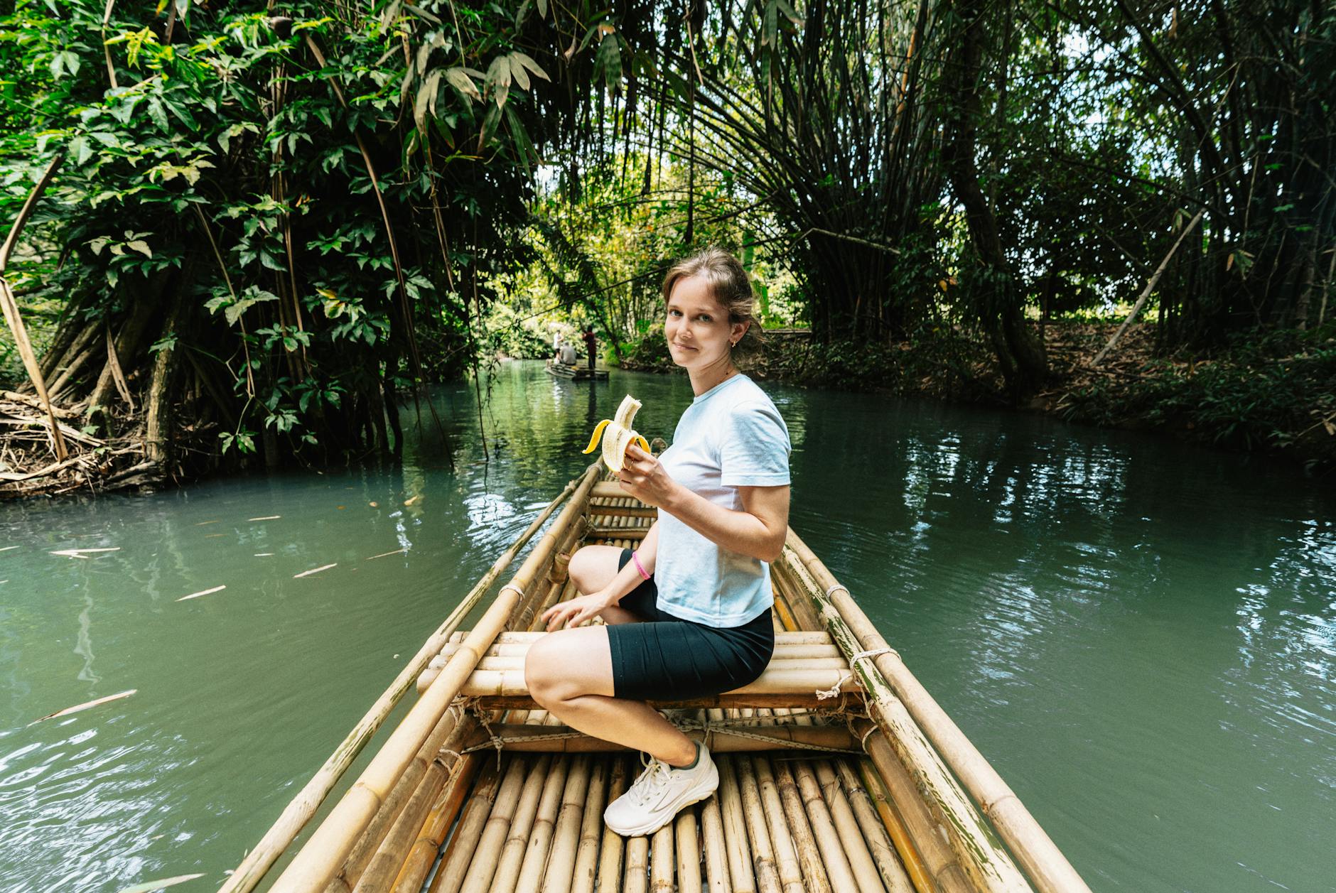 A traveler making a wish while gently releasing a krathong onto a moonlit river