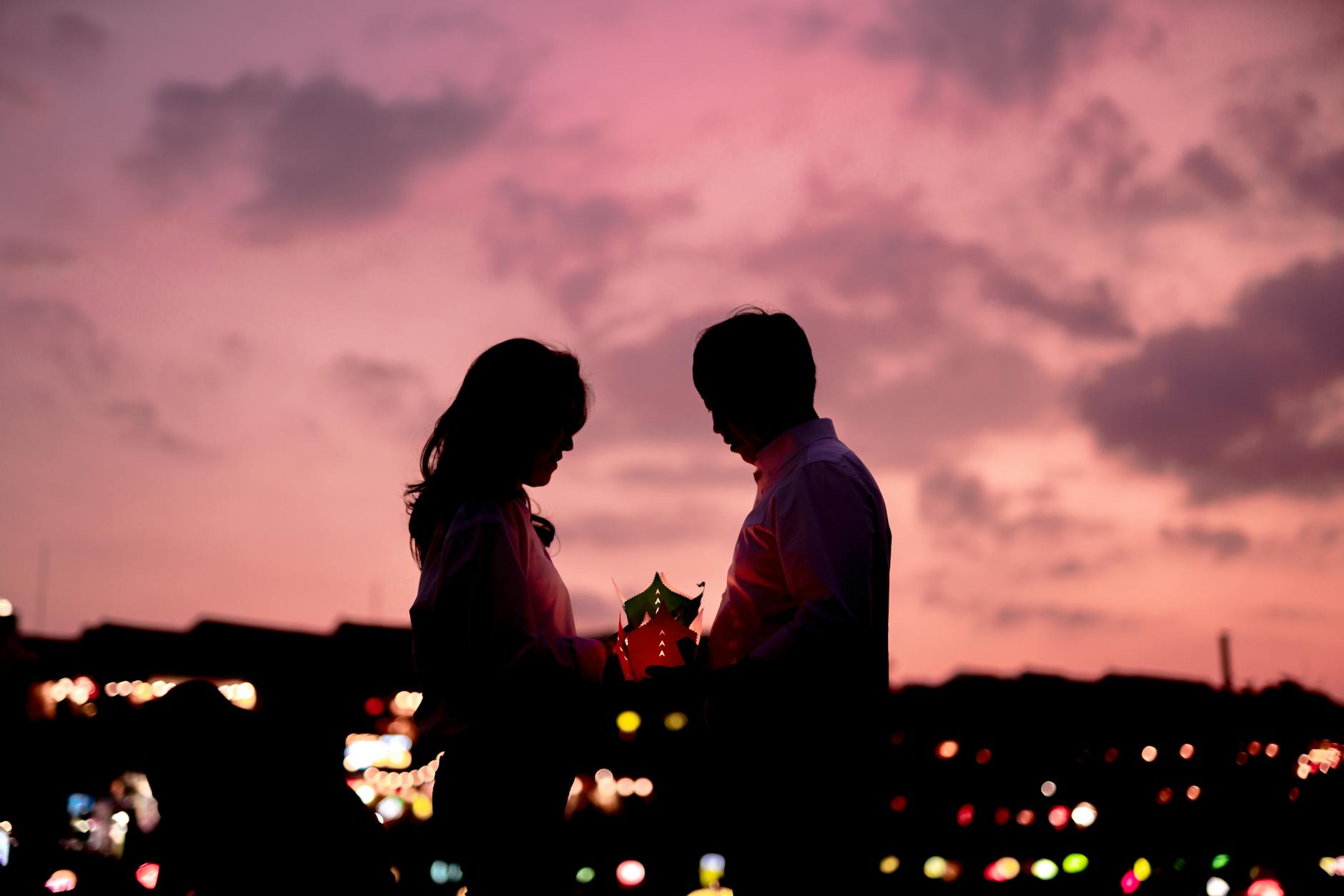 A family releasing a lantern together while standing by the river, with warm candlelight illuminating their faces