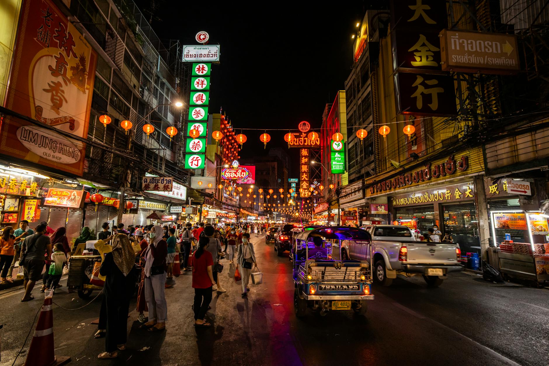 Crowds of festival-goers along the Ping River at night, with krathongs floating and lanterns rising above