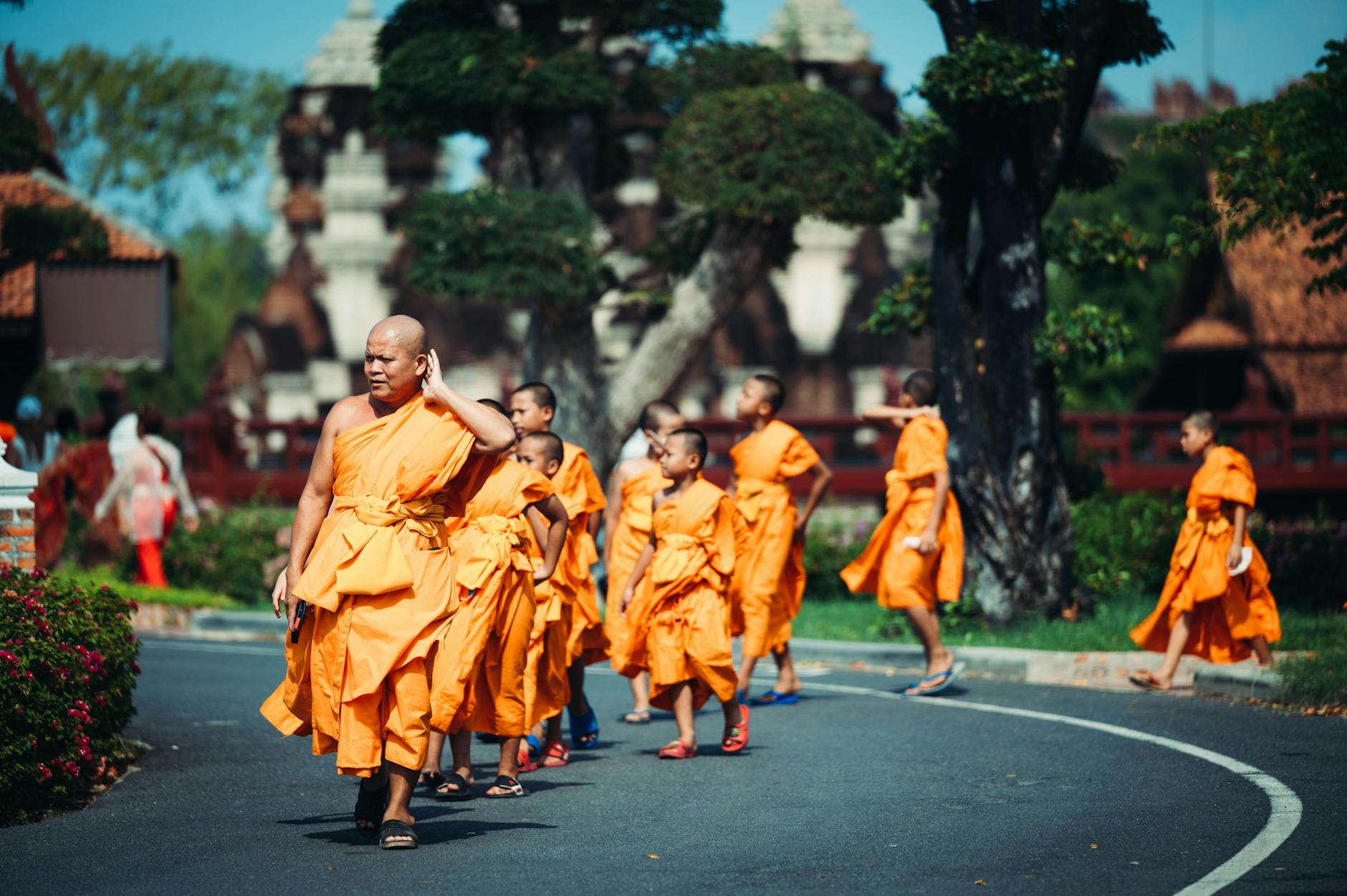 Thai monks in orange robes lighting candles during Makha Bucha Day ceremony at a temple