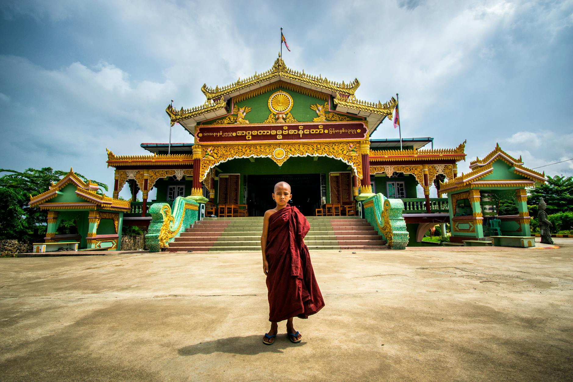A Shan boy having his head shaved by a monk inside the temple ordination hall as family members watch