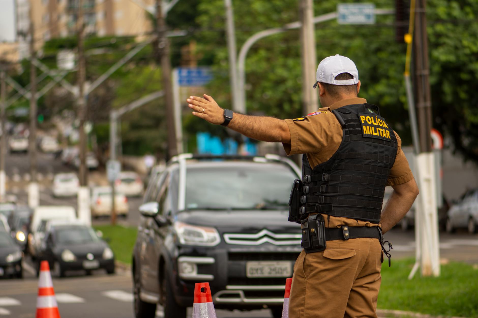 Police officer directing traffic at a Songkran checkpoint with water-splashed streets