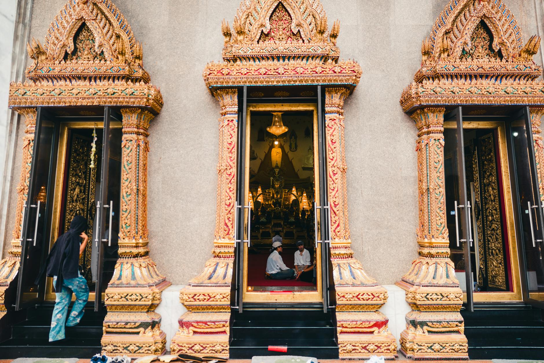 Tourists dressed in modest, temple-appropriate clothing receiving a sarong wrap from a temple attendant at the entrance gate