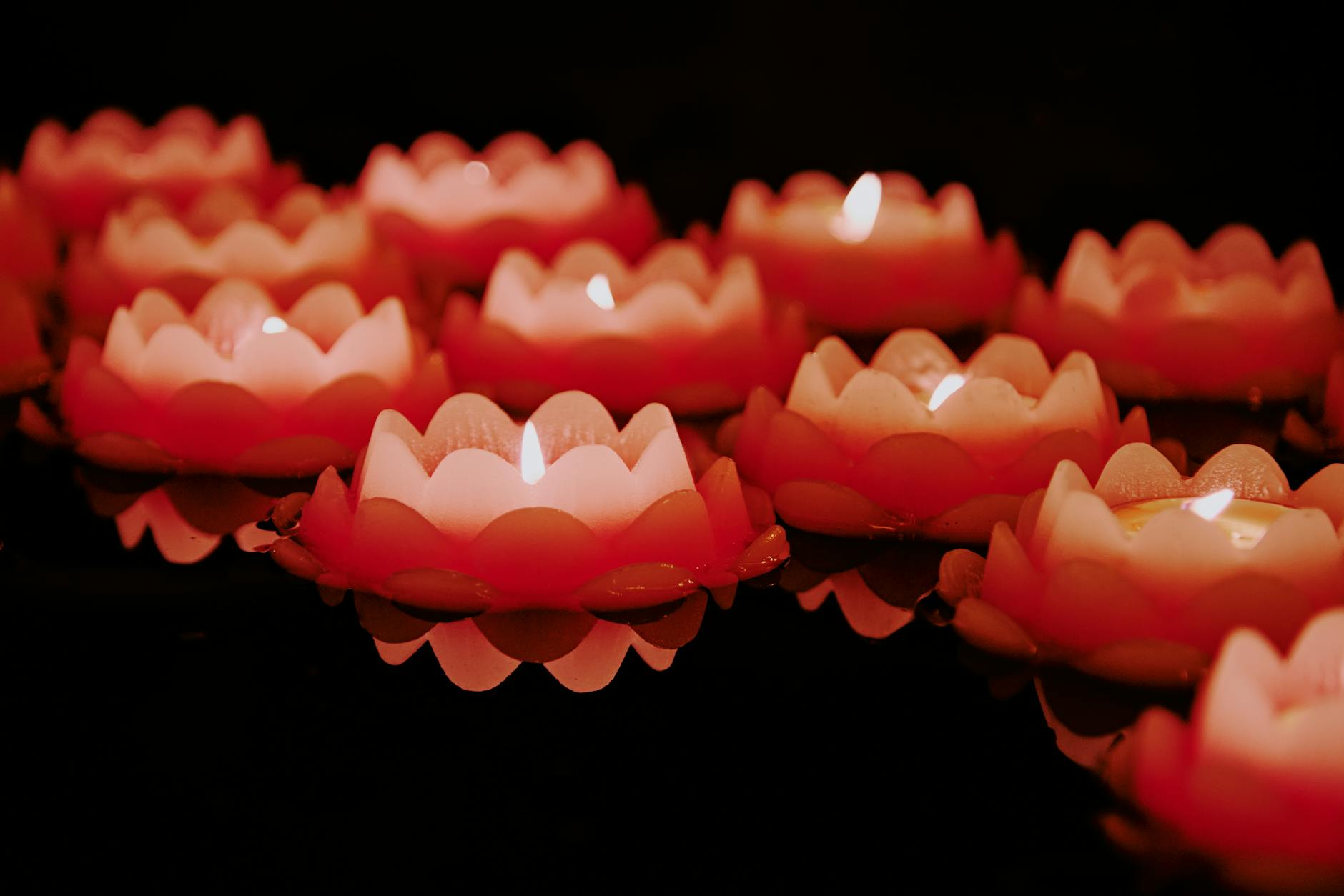 Thousands of glowing krathongs floating on a dark river under a night sky filled with paper lanterns during Loy Krathong and Yi Peng