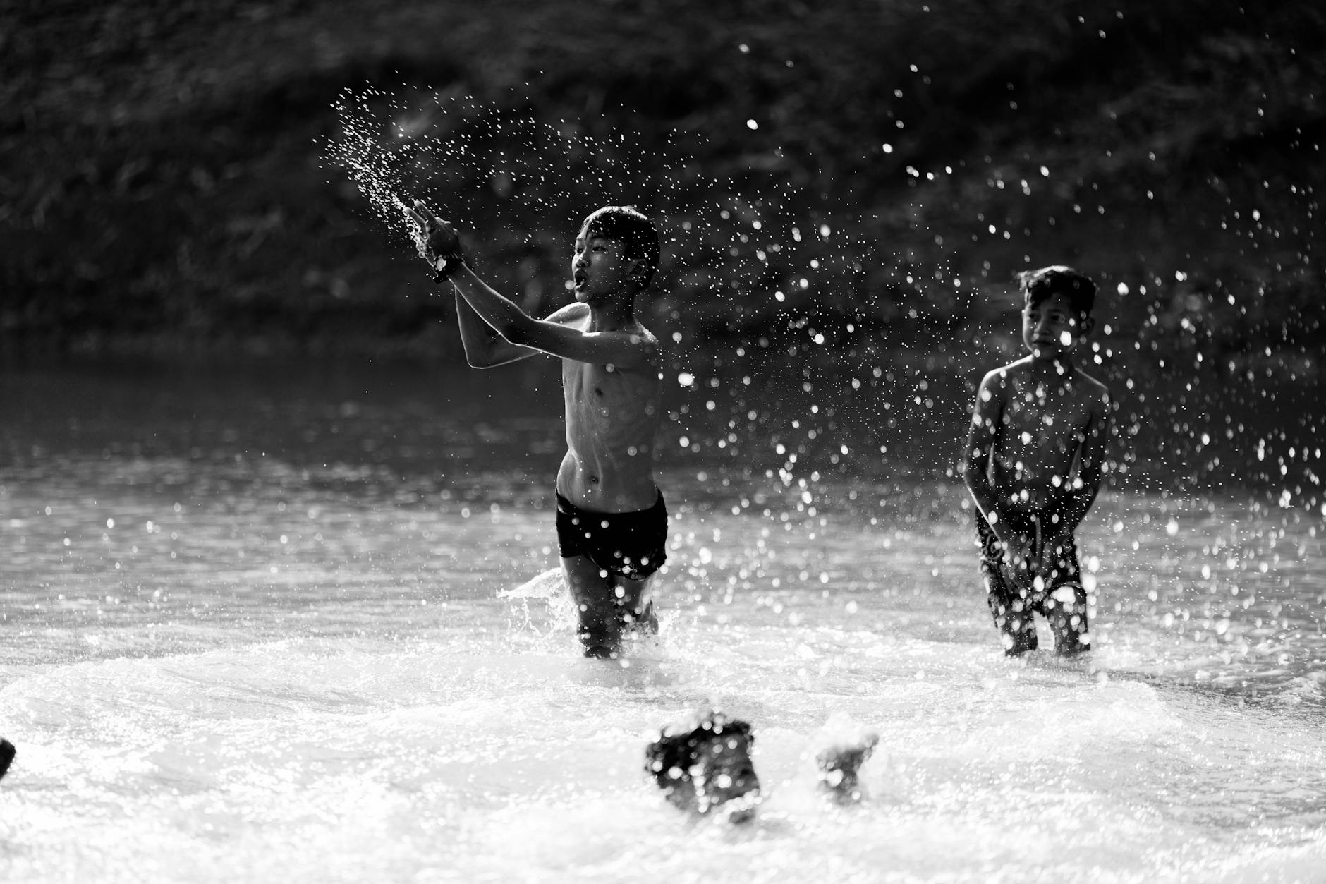 A joyful water fight on the streets of Bangkok during Songkran, with people splashing water from buckets and water guns amid a sea of colorful floral shirts